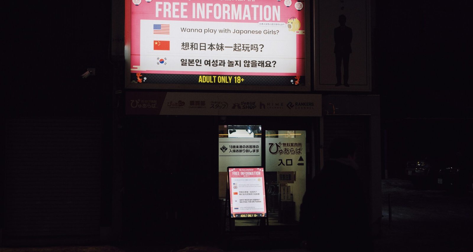 Leuchtschild mit der Aufschrift Free Information in mehreren Sprachen, fotografiert auf einer urbanen Straße