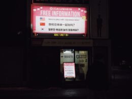 Leuchtschild mit der Aufschrift Free Information in mehreren Sprachen, fotografiert auf einer urbanen Straße