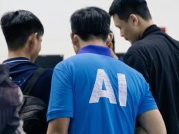 Mann in einem blauen Nike-Crewneck-T-Shirt steht frontal vor hellem, neutralem Hintergrund