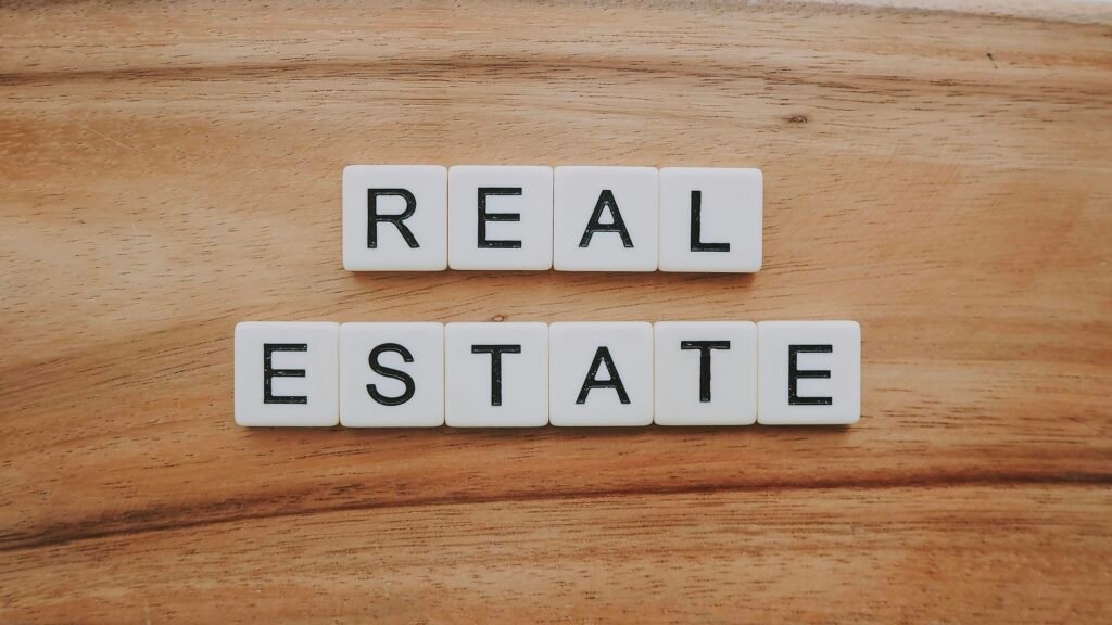 Nahaufnahme von Holzblöcken mit dem Schriftzug 'Real Estate' als Symbol für Immobilien und Digitalisierung