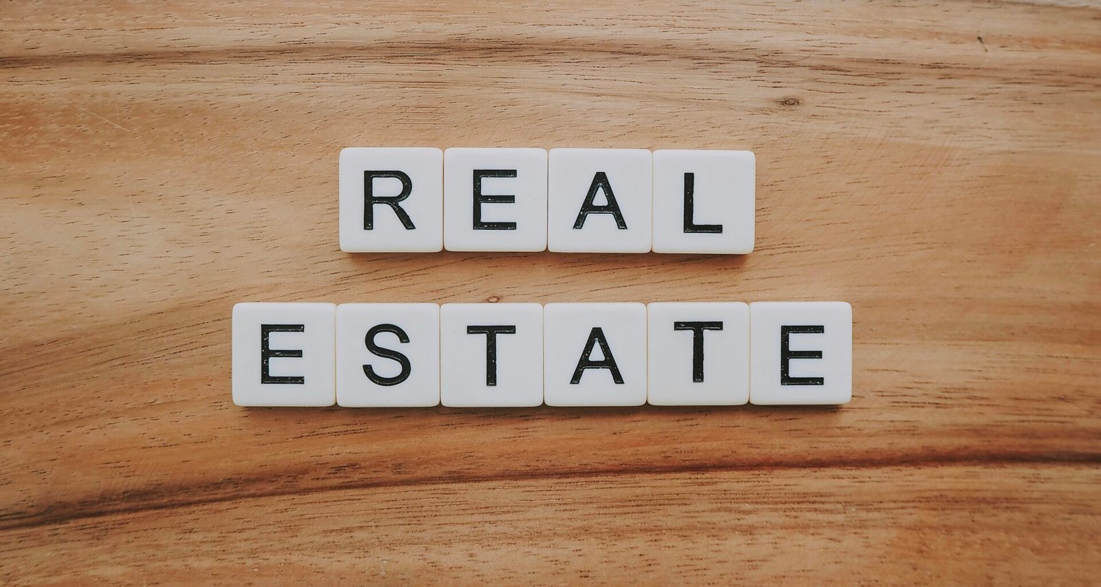 Nahaufnahme von Holzblöcken mit dem Schriftzug 'Real Estate' als Symbol für Immobilien und Digitalisierung