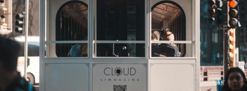 Mehrere Personen fahren tagsüber mit einer Straßenbahn durch das urbane Zentrum einer Großstadt.