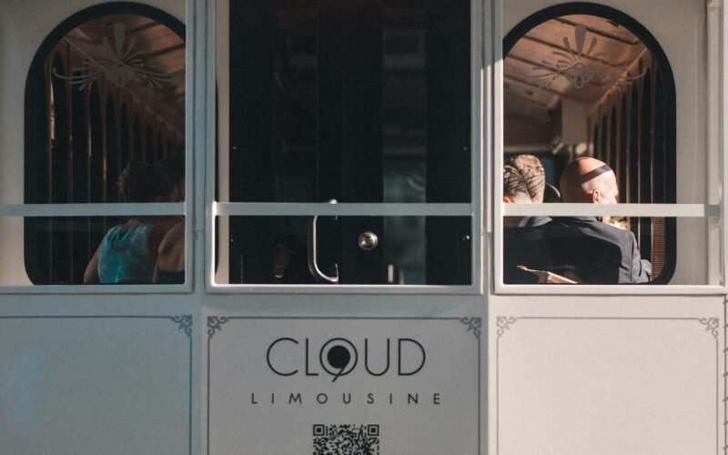 Mehrere Personen fahren tagsüber mit einer Straßenbahn durch das urbane Zentrum einer Großstadt.