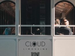 Menschen sitzen und stehen in einer Straßenbahn, die tagsüber durch eine urbane Umgebung fährt