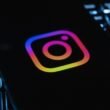 Instagram-Logo auf dunklem Hintergrund, beleuchtet von einer Computertastatur mit bunten Lichtern, Symbol für digitale Vernetzung