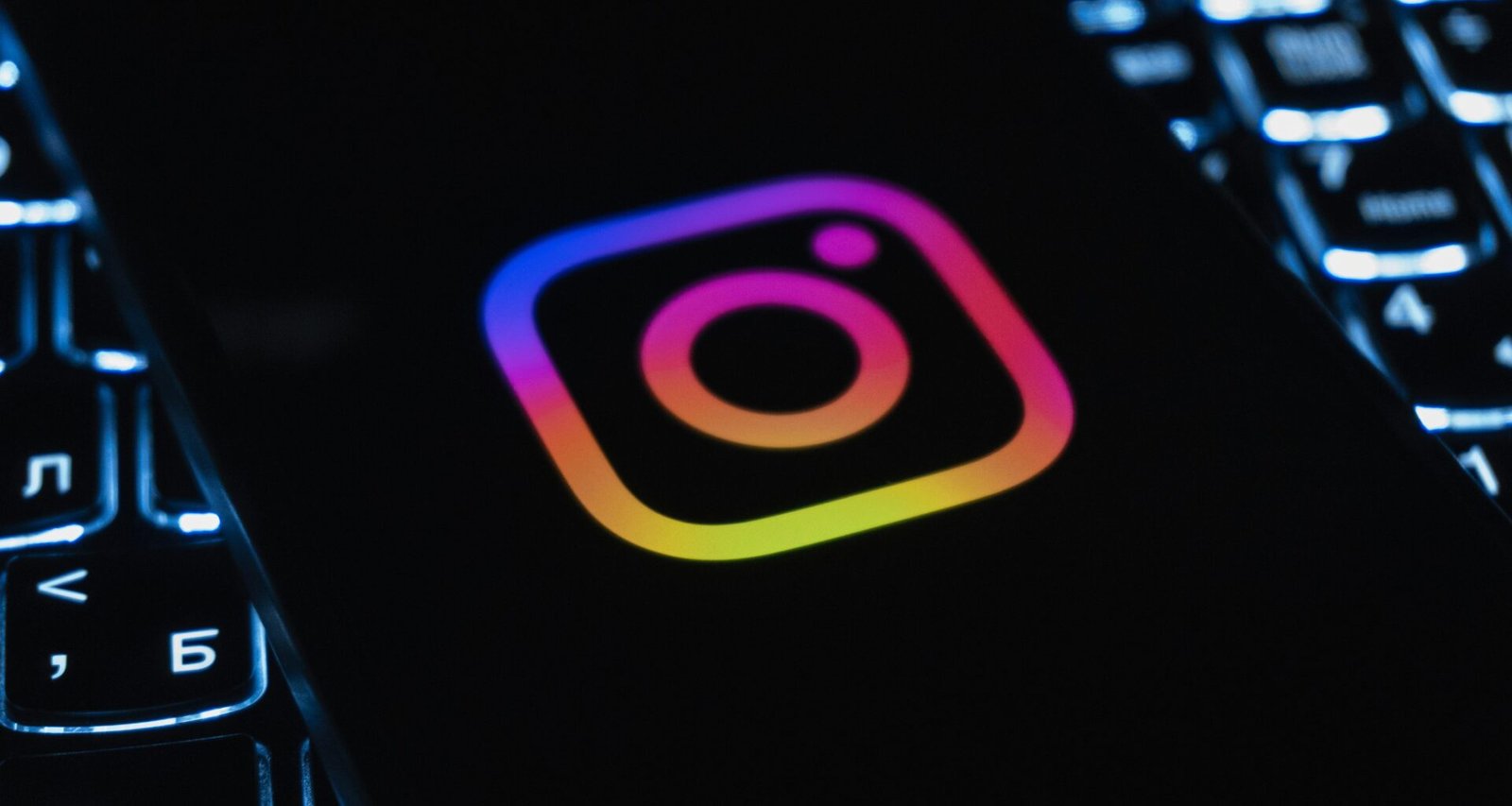 Instagram-Logo auf dunklem Hintergrund, beleuchtet von einer Computertastatur mit bunten Lichtern, Symbol für digitale Vernetzung