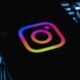 Instagram-Logo auf dunklem Hintergrund, beleuchtet von einer Computertastatur mit bunten Lichtern, Symbol für digitale Vernetzung
