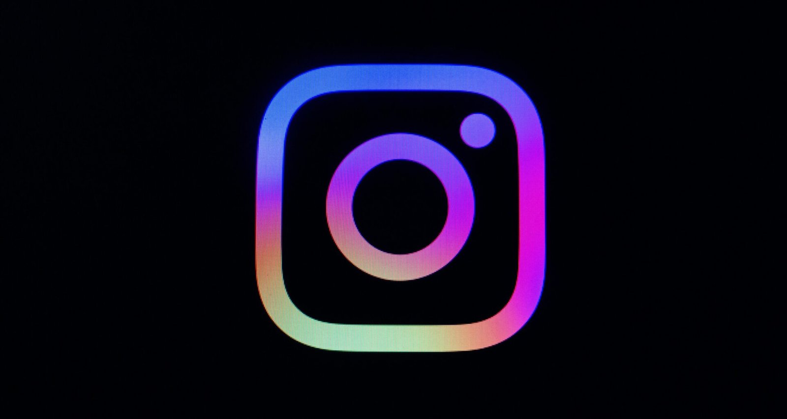Instagram Logo mit farbigem Verlauf auf schwarzem Hintergrund, Darstellung des bekannten Social-Media-Icons
