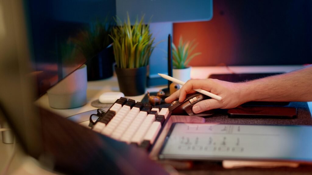 Person arbeitet konzentriert mit Computer und Maus an einem Schreibtisch, Fokus auf Hand und Eingabegerät.