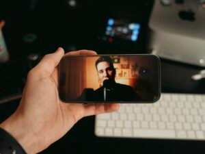 Eine Person hält ein Smartphone in der Hand und sieht sich ein Video auf dem Bildschirm an.