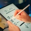 Jemand erstellt einen strukturierten Plan auf einem Tablet, ein Beispiel für digitale Arbeitsmethoden im Alltag.