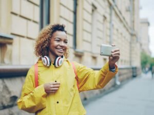 Junge Frau fotografiert sich selbst mit dem Handy im Innenbereich, Beispiel für moderne Smartphone-Nutzung
