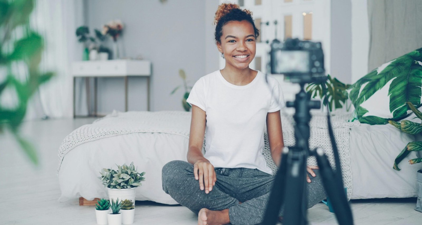 Junge Frau sitzt vor einer Kamera und filmt sich selbst für Online-Content oder Social-Media-Beiträge.