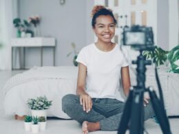 Junge Frau sitzt vor einer Kamera und filmt sich selbst für Online-Content oder Social-Media-Beiträge.