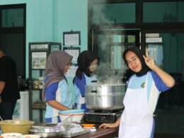 Gruppe junger Menschen kocht und dämpft Lebensmittel in moderner Küche. Küchenutensilien und Zutaten sind auf dem Tisch verteilt.