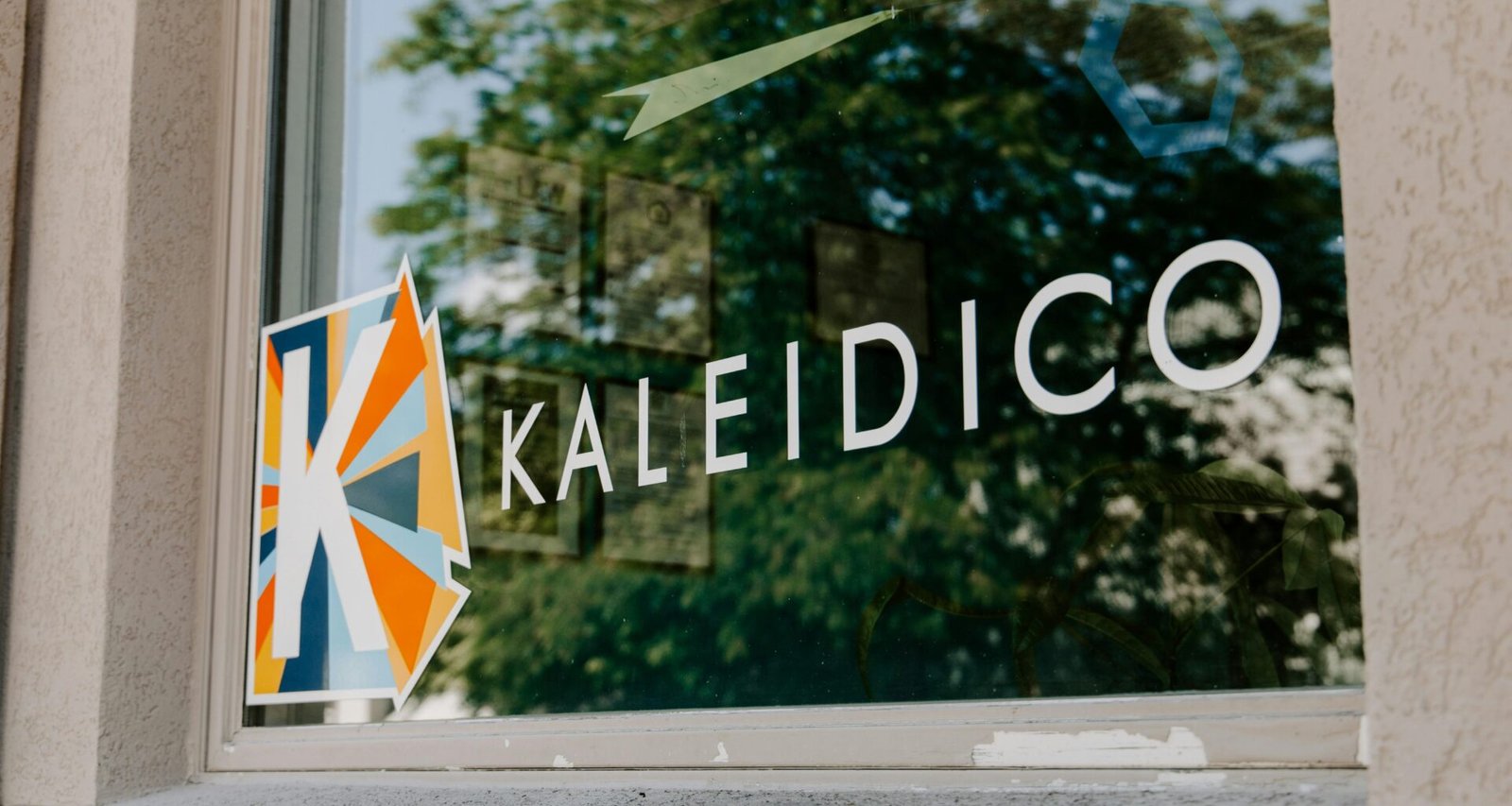 Gläsernes Firmenlogo als stilvolle Signage-Lösung im Innenbereich, fotografiert von Kaleidico.