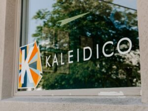 Gläsernes Firmenlogo als stilvolle Signage-Lösung im Innenbereich, fotografiert von Kaleidico.