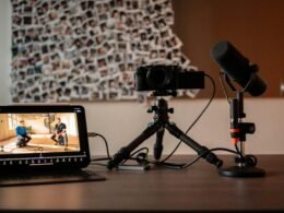 Kamera, Mikrofon und Monitor stehen auf einem modernen Schreibtisch – technische Ausstattung für Multimedia-Anwendungen.