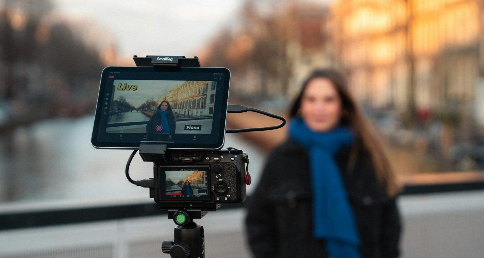 Kamera-Setup auf einem Stativ mit Frau im Hintergrund nahe einem Kanal, Fokus auf Technik und kreative Arbeit