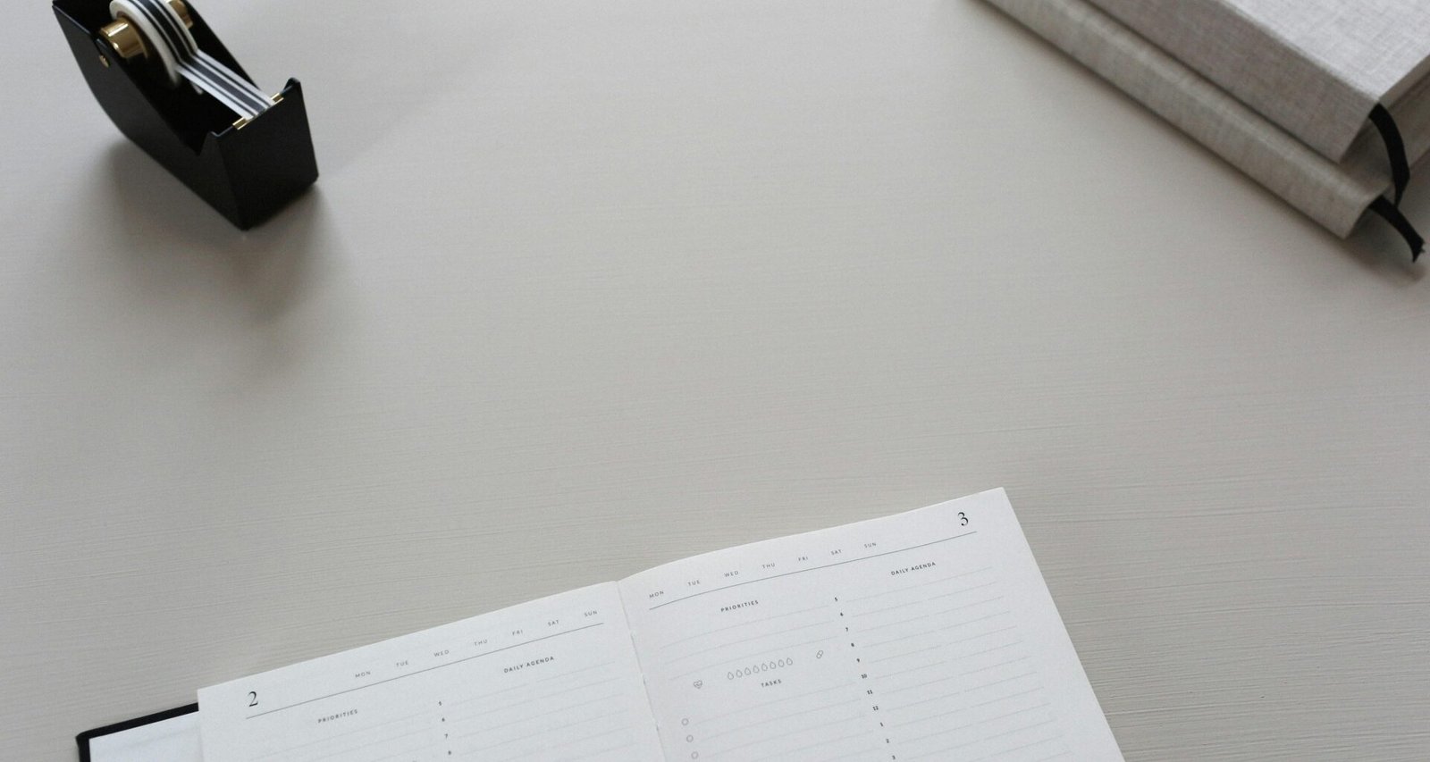 Tape-Dispenser und aufgeschlagenes Buch nebeneinander auf einem Schreibtisch, im Büro eingesetzt