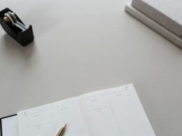 Tape-Dispenser und aufgeschlagenes Buch nebeneinander auf einem Schreibtisch, im Büro eingesetzt