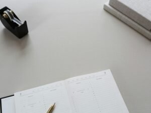 Tape-Dispenser und aufgeschlagenes Buch nebeneinander auf einem Schreibtisch, im Büro eingesetzt