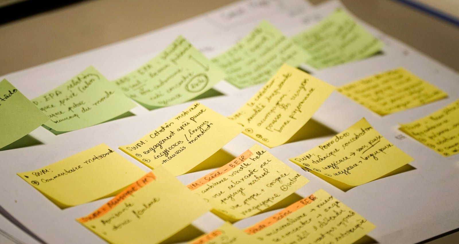 Mehrere bunte Sticky Notes mit handgeschriebenem Text liegen nebeneinander auf einer ebenen Fläche arrangiert.