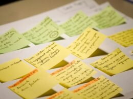 Mehrere bunte Sticky Notes mit handgeschriebenem Text liegen nebeneinander auf einer ebenen Fläche arrangiert.