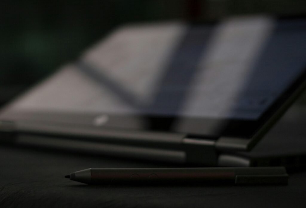 Schwarzer und silberner Klickkugelschreiber liegt auf einem hellen Untergrund, Fokus auf die Spitze des Stifts