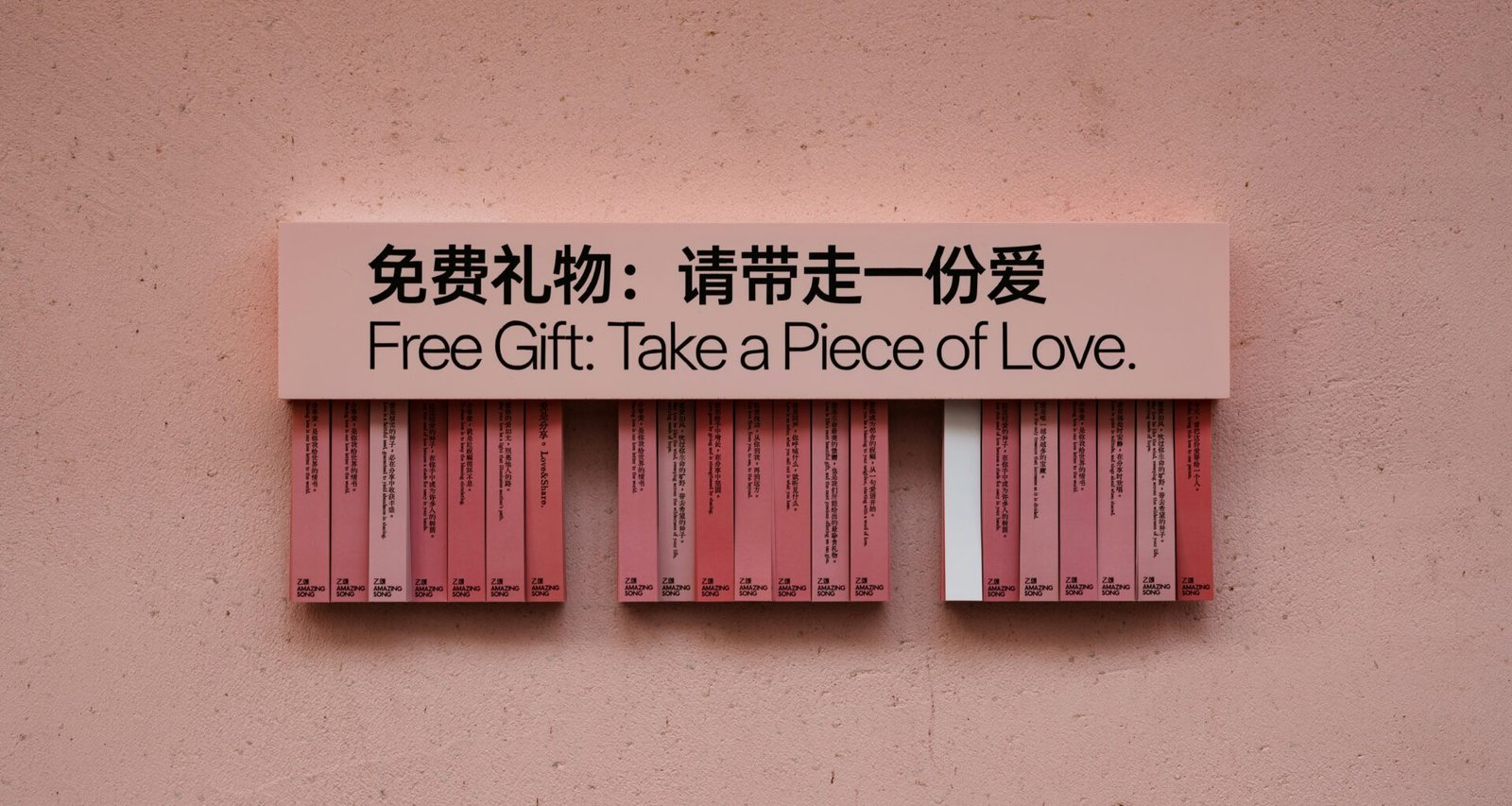 Stück rotes Papier mit Aufschrift 'a piece of love' als Geschenk auf hellem Untergrund