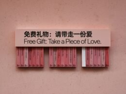 Nahaufnahme einer Hand, die ein kleines Herzgeschenk hält, auf neutralem Hintergrund