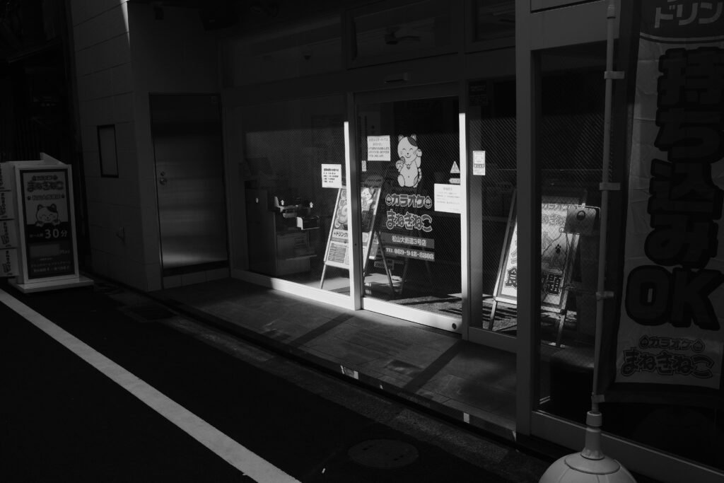 Nächtliches Schaufenster mit Licht, das auf den Gehweg fällt – moderne Storefront und urbane Atmosphäre