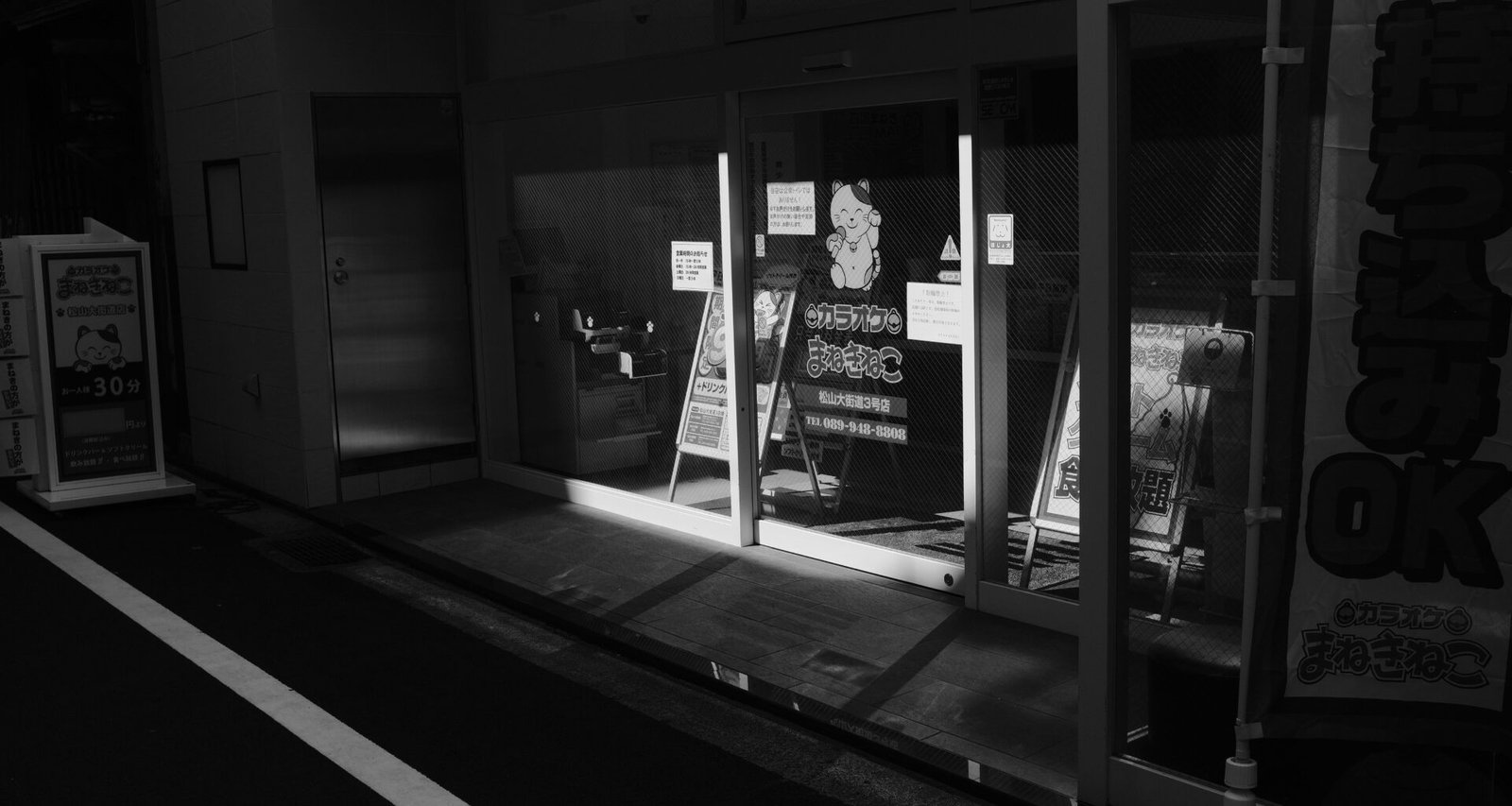 Nächtliches Schaufenster mit Licht, das auf den Gehweg fällt – moderne Storefront und urbane Atmosphäre