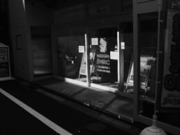 Nächtliches Schaufenster mit Licht, das auf den Gehweg fällt – moderne Storefront und urbane Atmosphäre