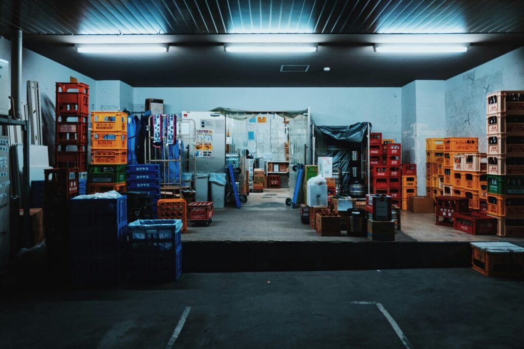 Mehrere gestapelte Kunststoffkisten in einer Garage, fotografiert aus seitlicher Perspektive mit natürlichem Lichteinfall.