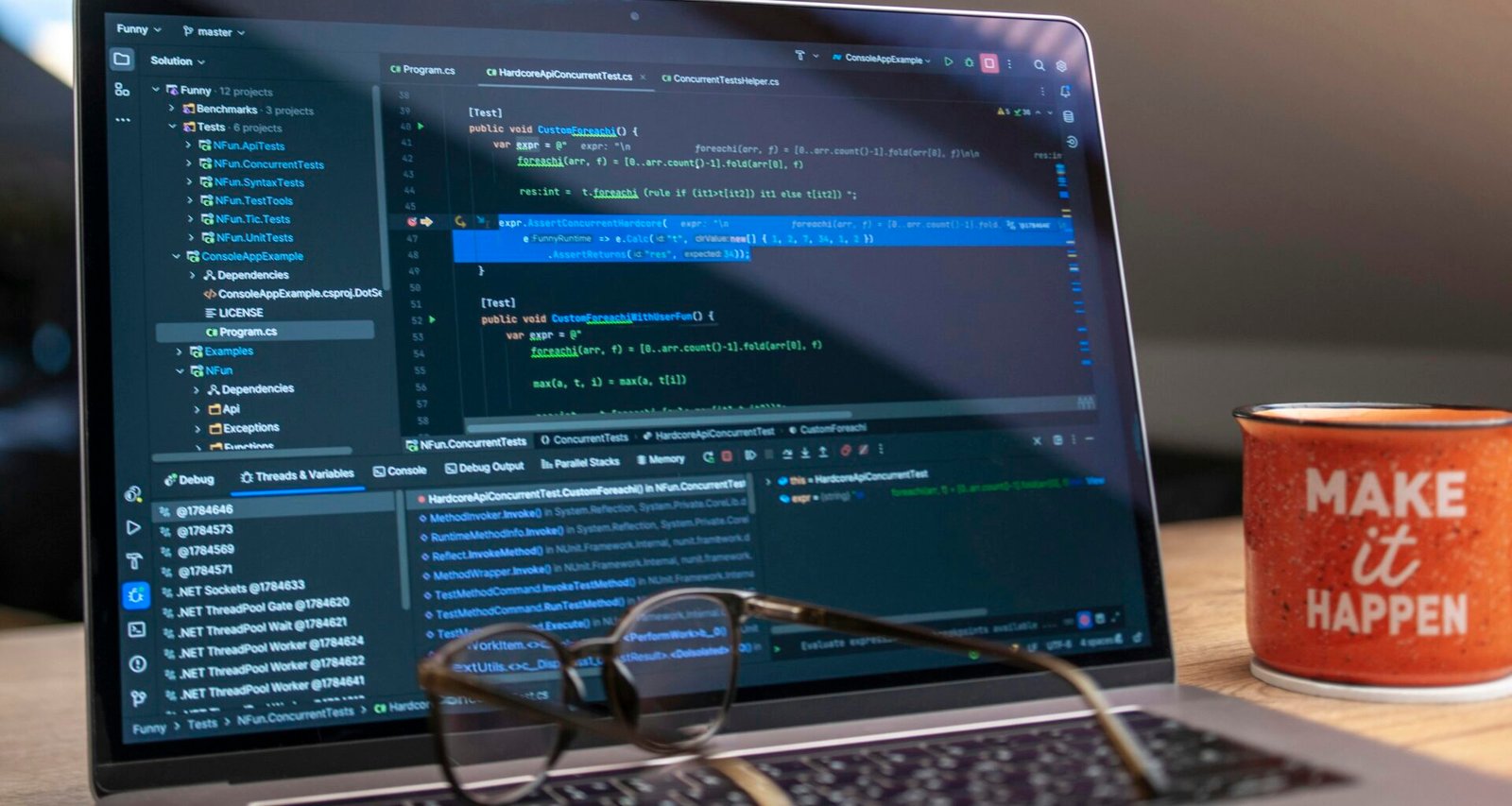 Laptop mit offenem Code auf dem Bildschirm, daneben eine Brille und eine Kaffeetasse auf einem Schreibtisch