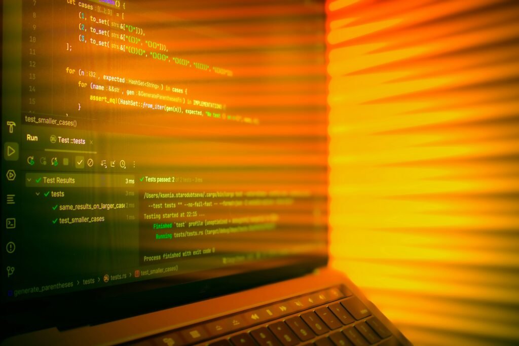 Laptop-Bildschirm mit geöffnetem Code-Editor und orangefarbenem Leuchten im Hintergrund, geeignet für IT-Themen