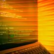 Laptopbildschirm mit sichtbarem Quellcode und orangefarbenem Licht, ideal für Themen zu Programmierung und Webentwicklung