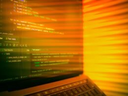 Laptopbildschirm mit sichtbarem Quellcode und orangefarbenem Licht, ideal für Themen zu Programmierung und Webentwicklung