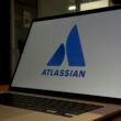 Ein aufgeklappter Laptop präsentiert groß das Atlassian-Logo auf dem Display, ideal für Artikel zur Teamarbeit und digitalen Tools.