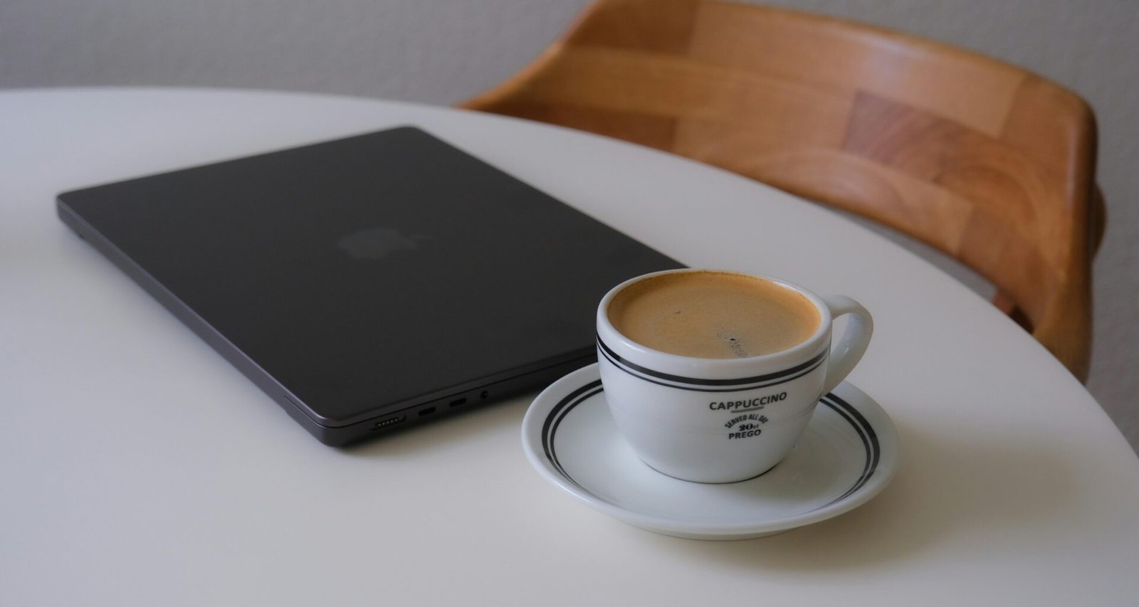 Laptop und Kaffeetasse stehen nebeneinander auf einem weißen Tisch, ideal für Homeoffice oder produktives Arbeiten.