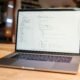 Laptop auf einem Tisch, auf dessen Bildschirm mehrere Zeilen Programmiercode angezeigt werden