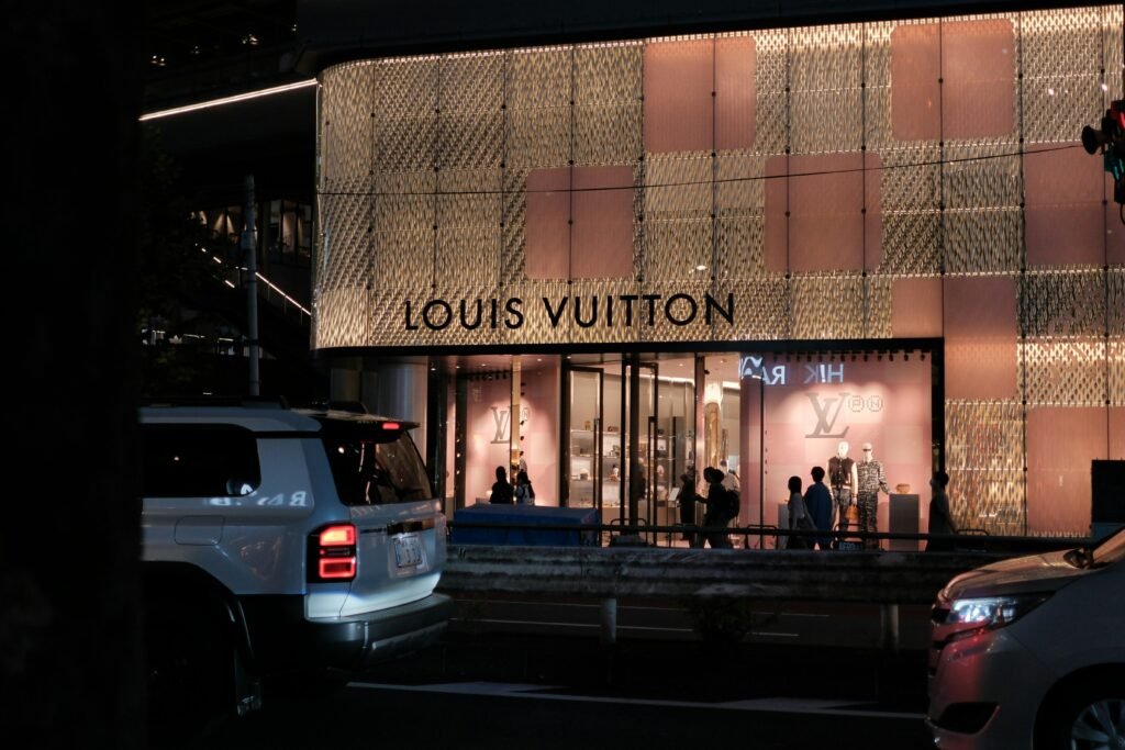 Louis Vuitton Geschäft bei Nacht, beleuchtete Fassade und Autos auf der Straße im urbanen Stadtbild