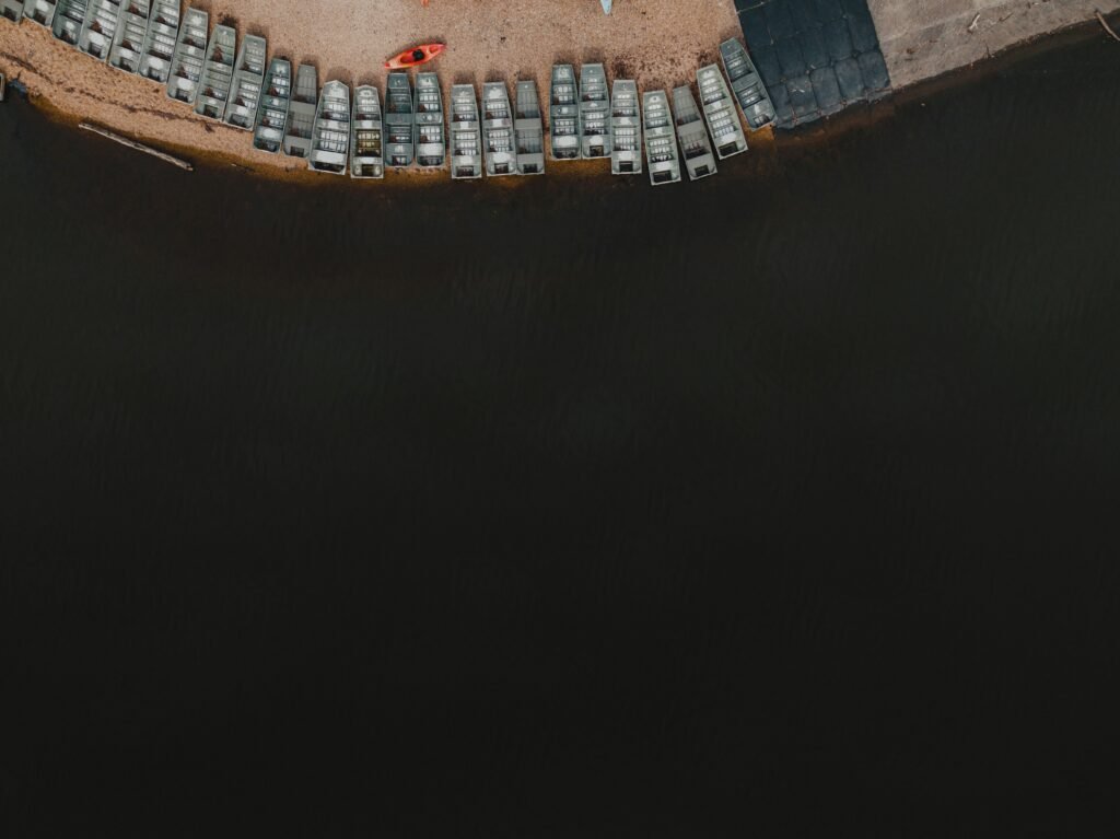 Luftaufnahme eines Parkplatzes am Ufer eines Gewässers mit klar erkennbaren Parkflächen und angrenzendem Wasser