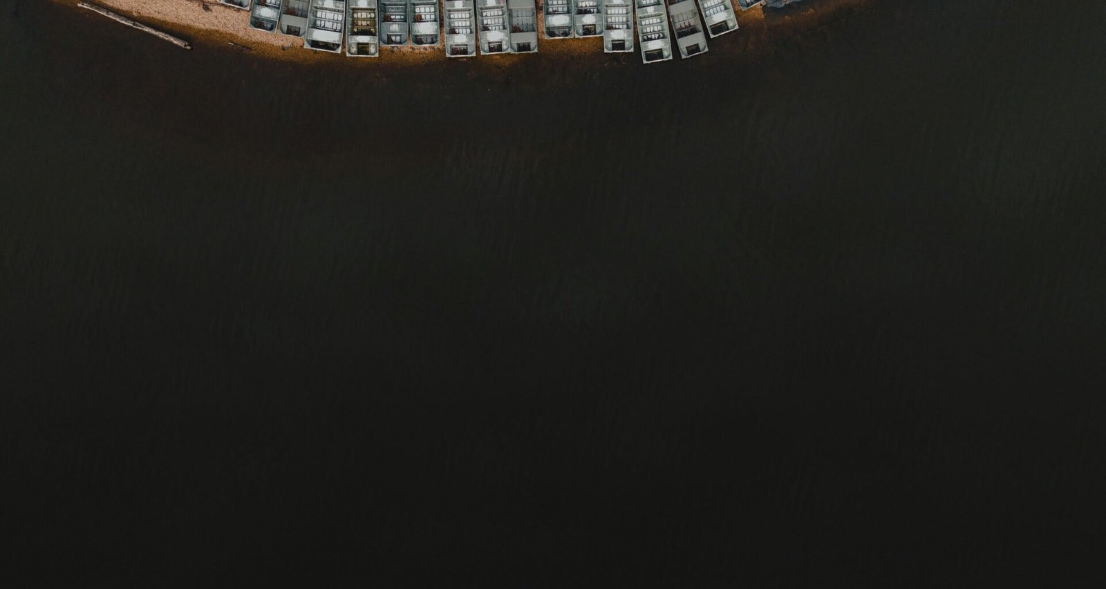 Luftaufnahme eines Parkplatzes am Ufer eines Gewässers mit klar erkennbaren Parkflächen und angrenzendem Wasser