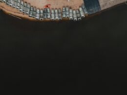 Luftaufnahme eines Parkplatzes am Ufer eines Gewässers mit klar erkennbaren Parkflächen und angrenzendem Wasser