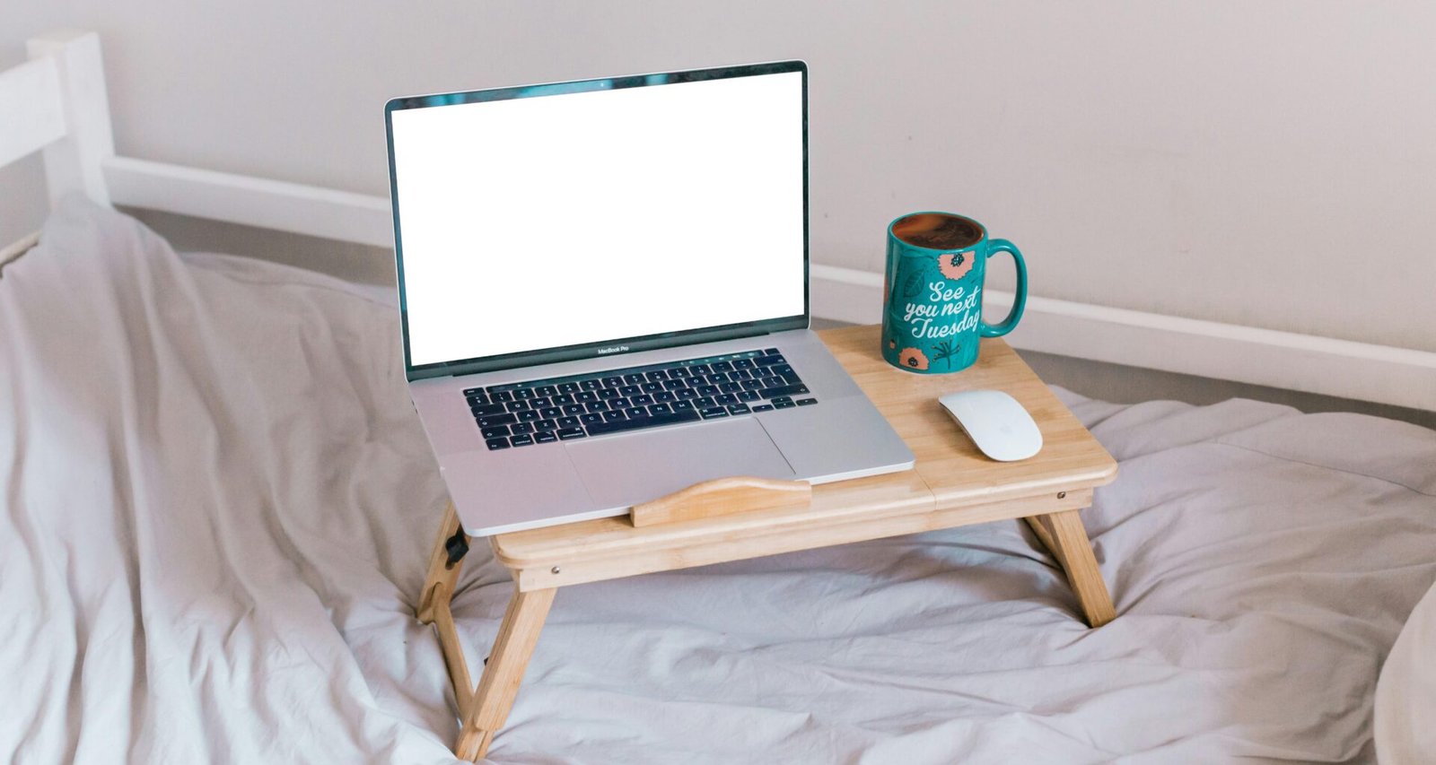 Ein MacBook Air steht geöffnet auf einem braunen Holztisch und zeigt einen typischen Arbeitsplatz im digitalen Zeitalter.
