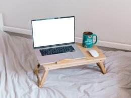Ein MacBook Air steht geöffnet auf einem braunen Holztisch und zeigt einen typischen Arbeitsplatz im digitalen Zeitalter.