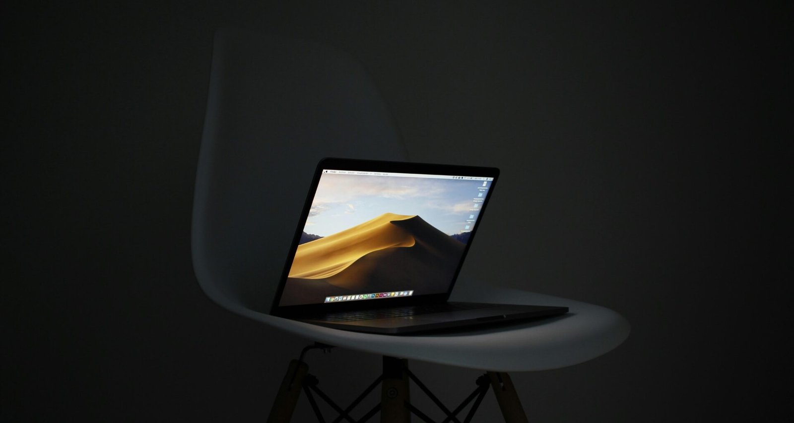 MacBook Pro, der auf einem schlichten Stuhl ruht – Symbol für mobiles und flexibles Arbeiten im digitalen Zeitalter