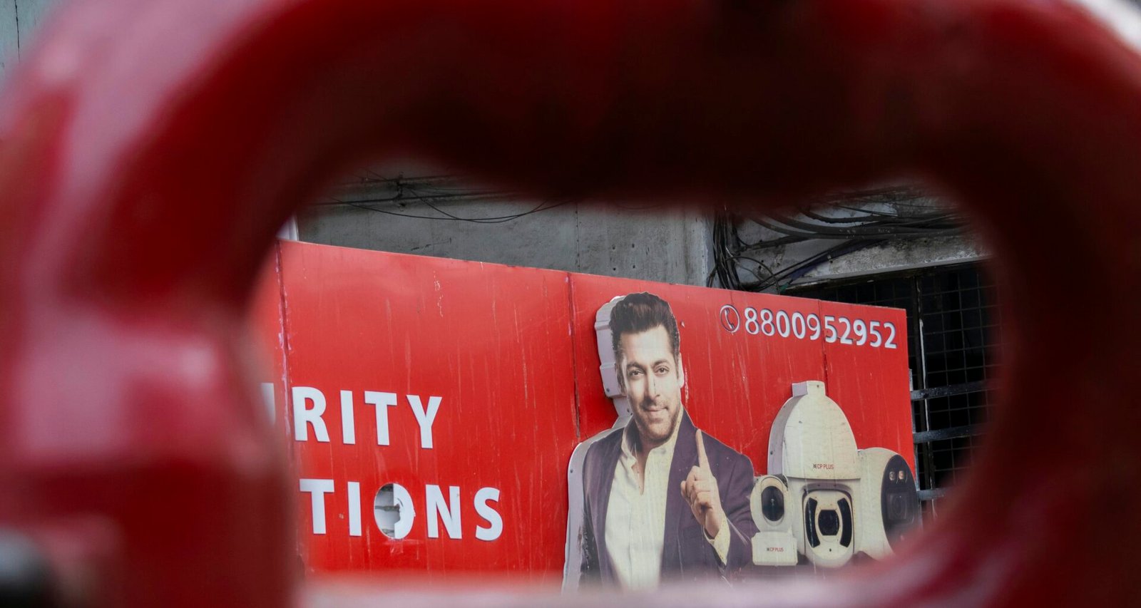 Ein Mann ist auf einem roten Werbeplakat im Stadtgebiet abgebildet, das moderne Werbemaßnahmen illustriert.